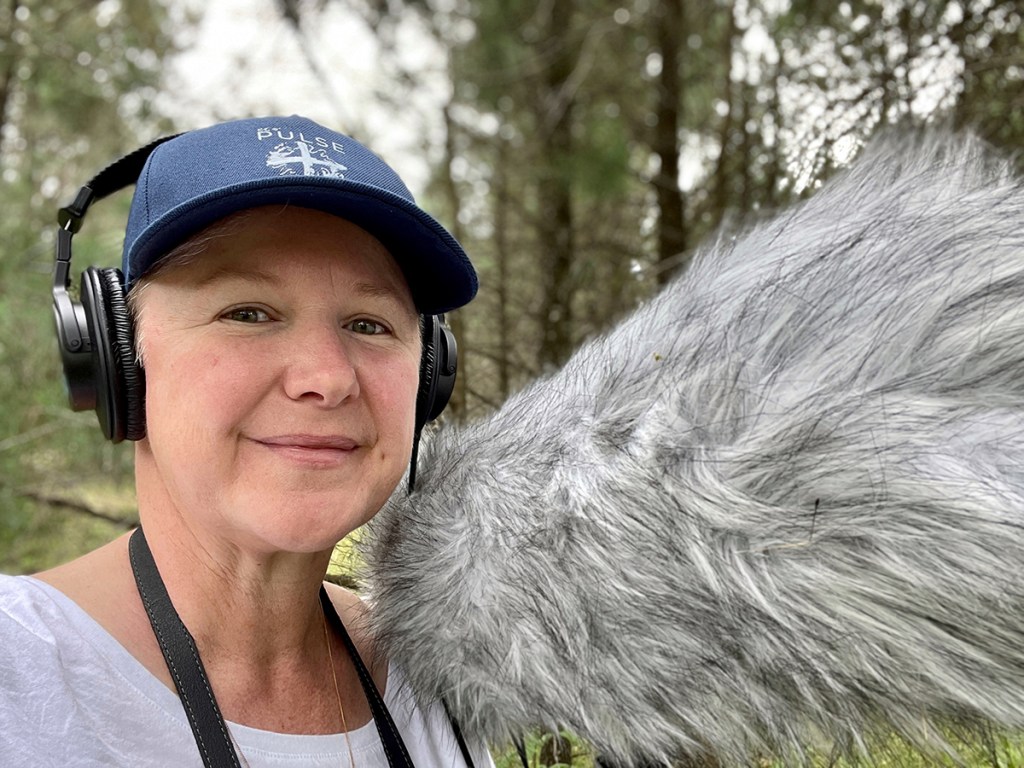 The artist and blog post author, Kim V. Goldsmith wearing headphones and holding a shotgun microphone with blimp and wombat wind shield