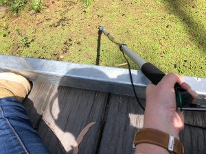 The artist using a hydrophone on a boom pole to record plants photosynthesising under water in the Marshes, in 2020